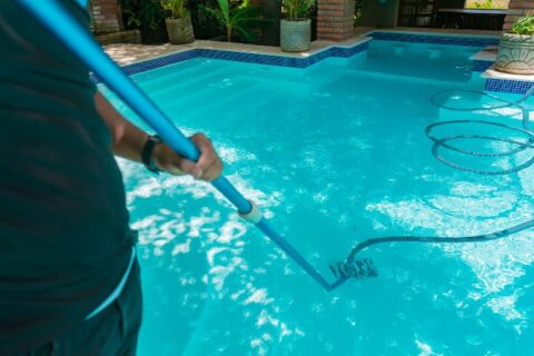 Man cleaning swimming pool with suction hose in VA & MD